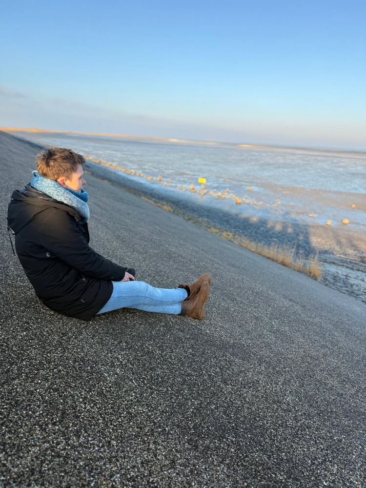 Saskia Ebbers zittend op een dijk met uitzicht over het wad